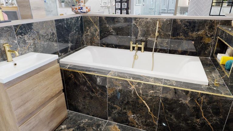 Dark marble effect tiles with gold veining around a bath