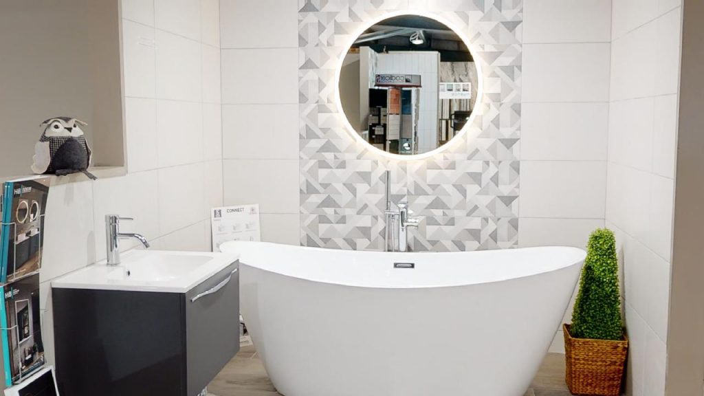 Round LED mirror above a freestanding bath in a showroom bathroom